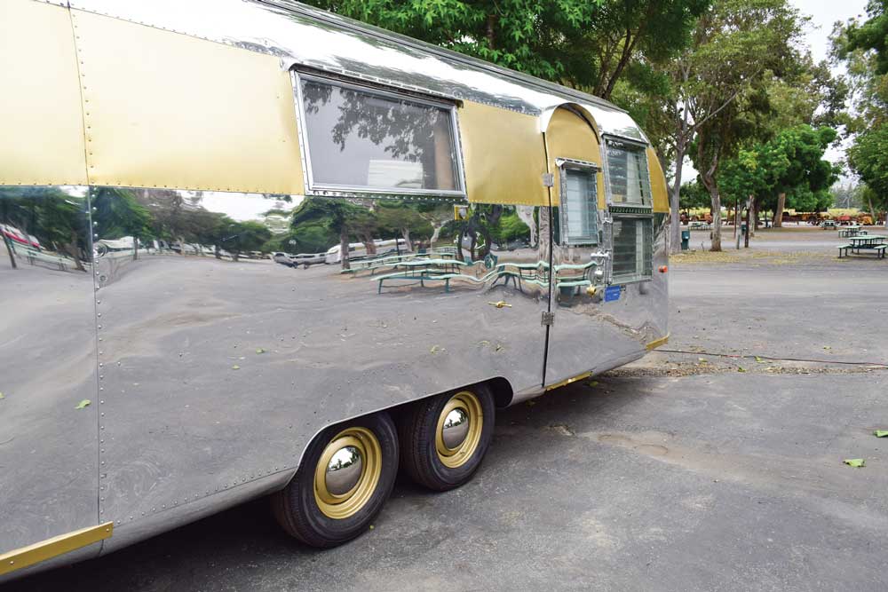Restored 1961 Airstream trailer exterior shows the gold wheel and gold stripe that runs the length of the trailer.