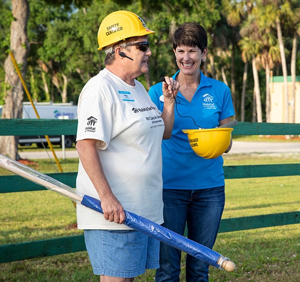 Mary Vandeveld wearing yellow hard hat and speaking into microphone.