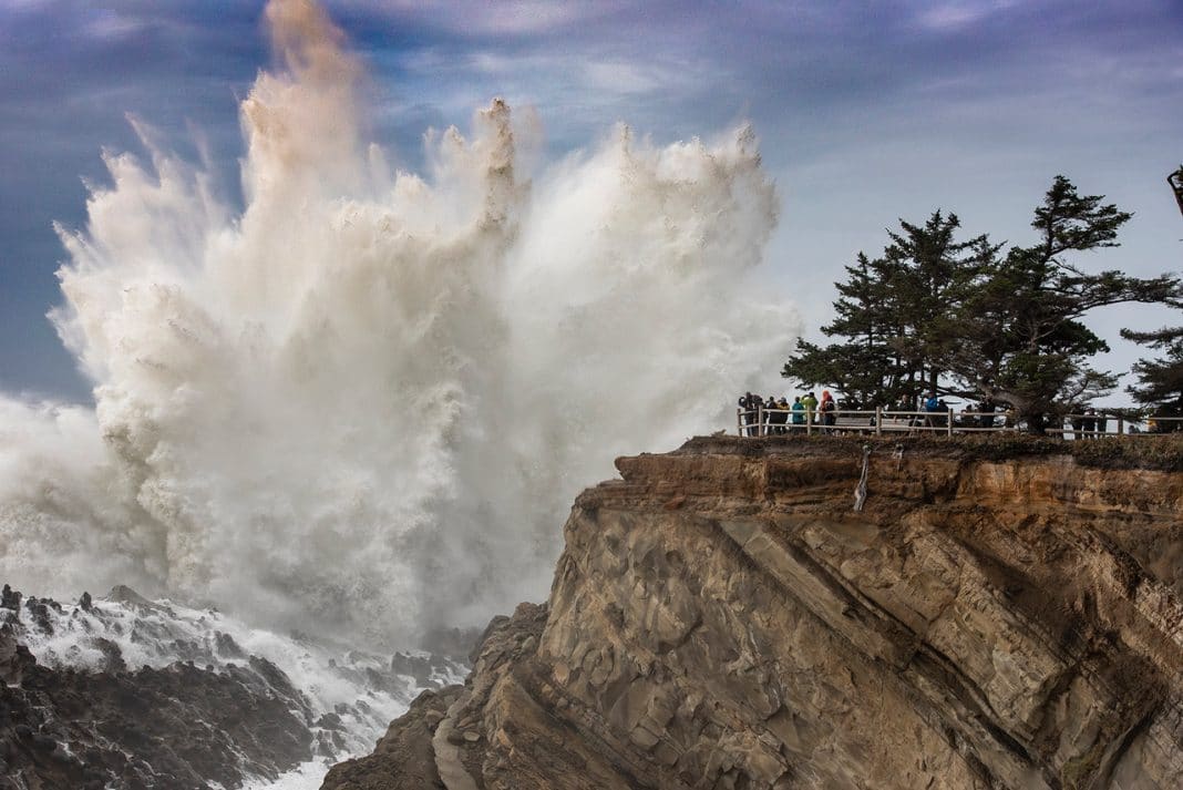 waves crash against oregon rocks with overlook of people watching