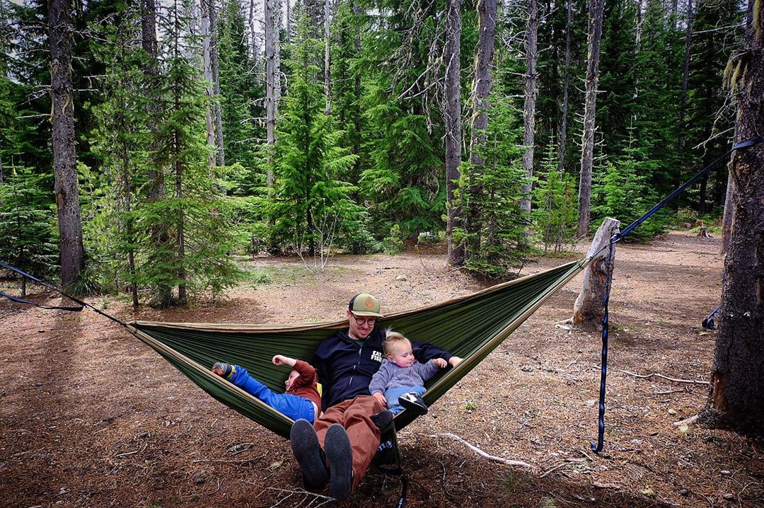Father and two small children in hammock in forest 