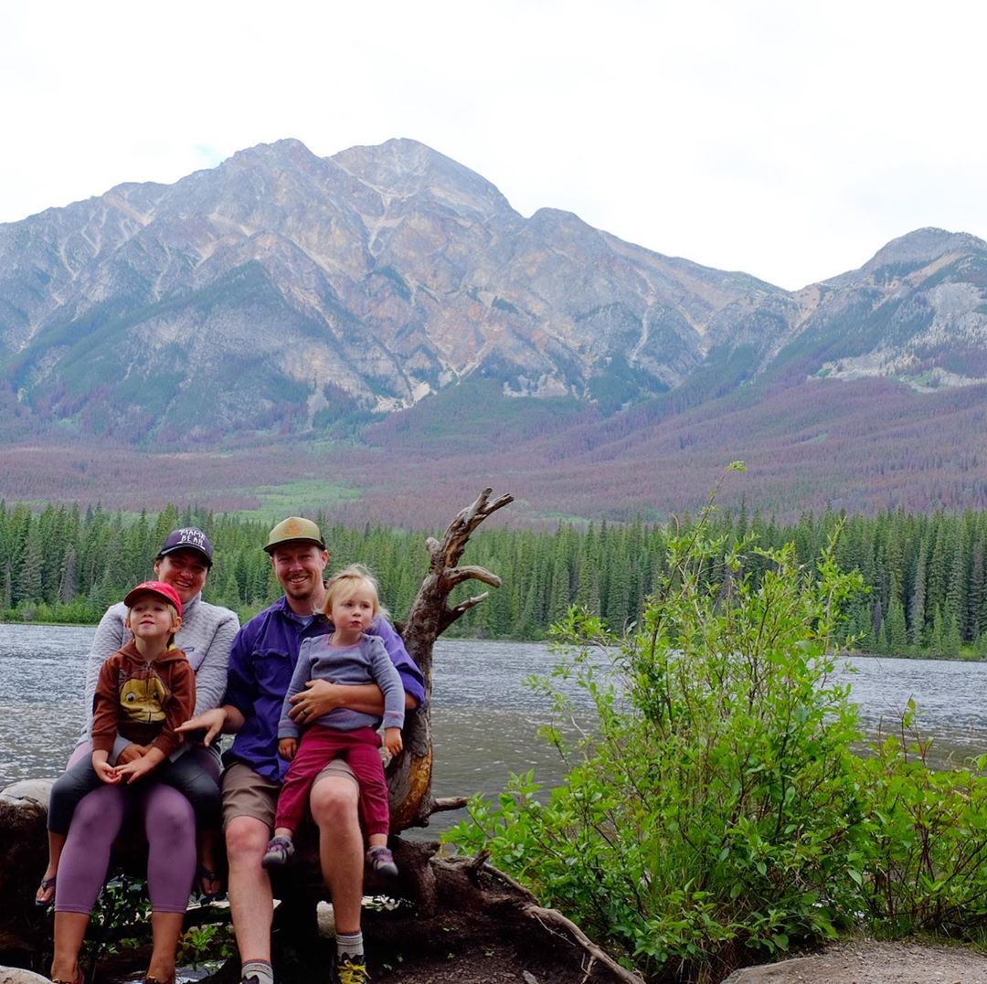 Family of four posing on log lakeside