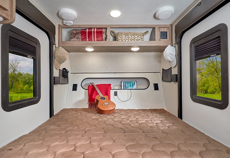 View toward the front interior of the Jayco Hummingbird 10RK showing the bed with a guitar on it.