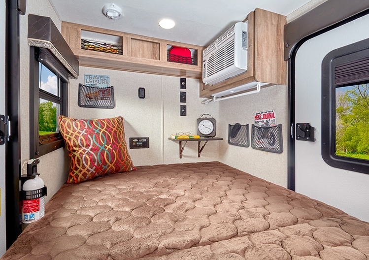 Inside view of the Jayco Hummingbird 10RK looking toward the rear with overhead storage and air-conditioning unit.