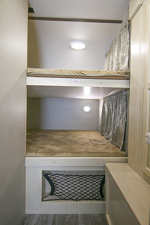 Bunk beds in the rear of the trailer with lighting inside and storage below.