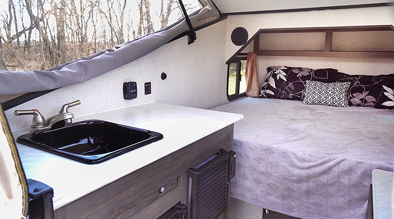 Inside the Clipper Express showing the sink, counter and bed with the pop-up extended.