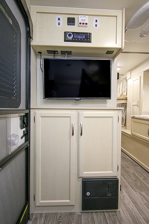 A flat-screen TV and cupboards in cream color.