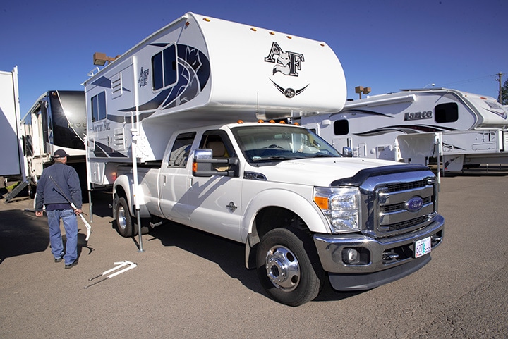 2015 F-350 Super Duty 4x4 dually at an RV dealership loaded with a new Arctic Fox truck camper
