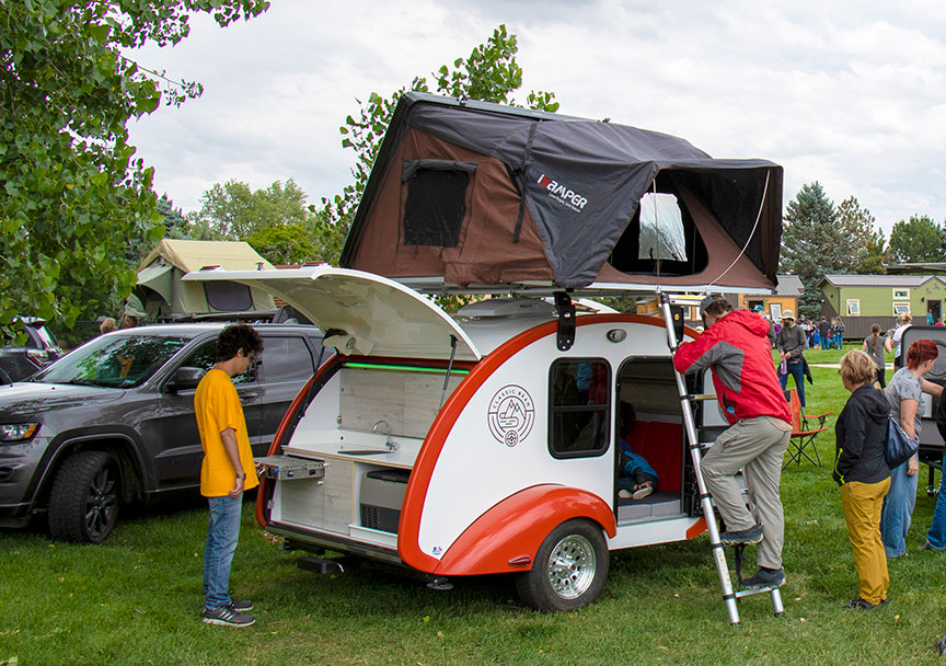 Classic Bean trailer with a rooftop tent accessed by man on ladder.