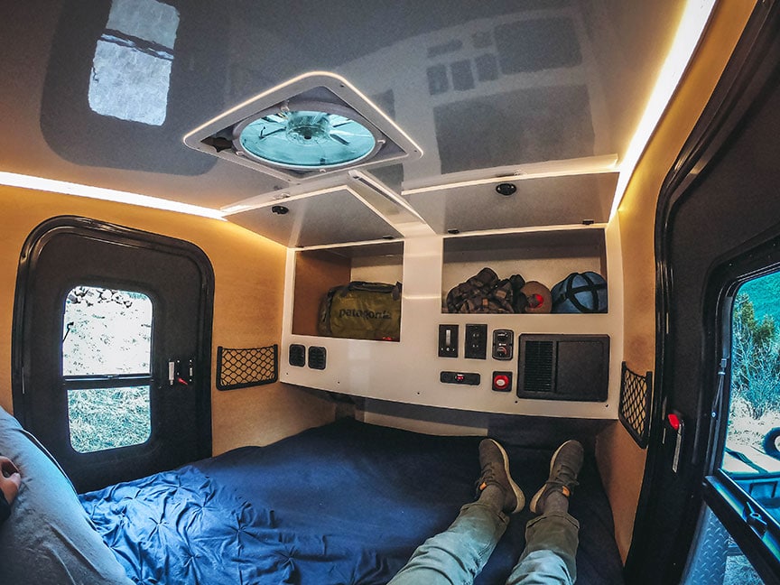 Person reclining on bed of trailer with cupboards straight ahead.