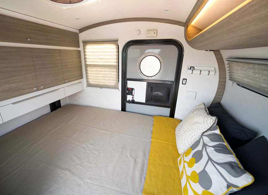 View inside Classic Bean cabin with queen mattress and shelves.