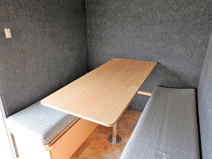 Inside the trailer with birch table, gray walls and bench seats