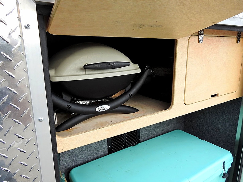 Rear kitchen with weber grill and turquoise cooler.