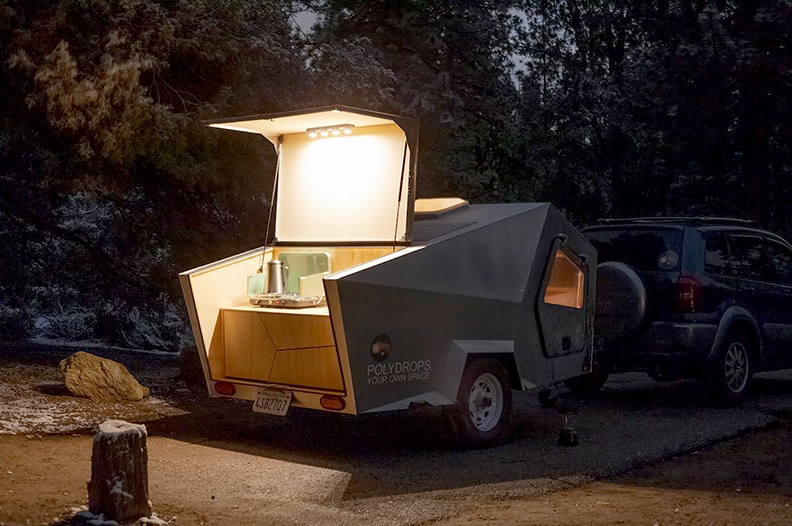 Rear hatch opens to reveal the kitchen , shown at night with lights.