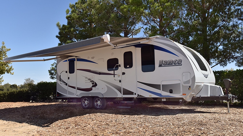 Exterior of white Lance trailer with awning extended.