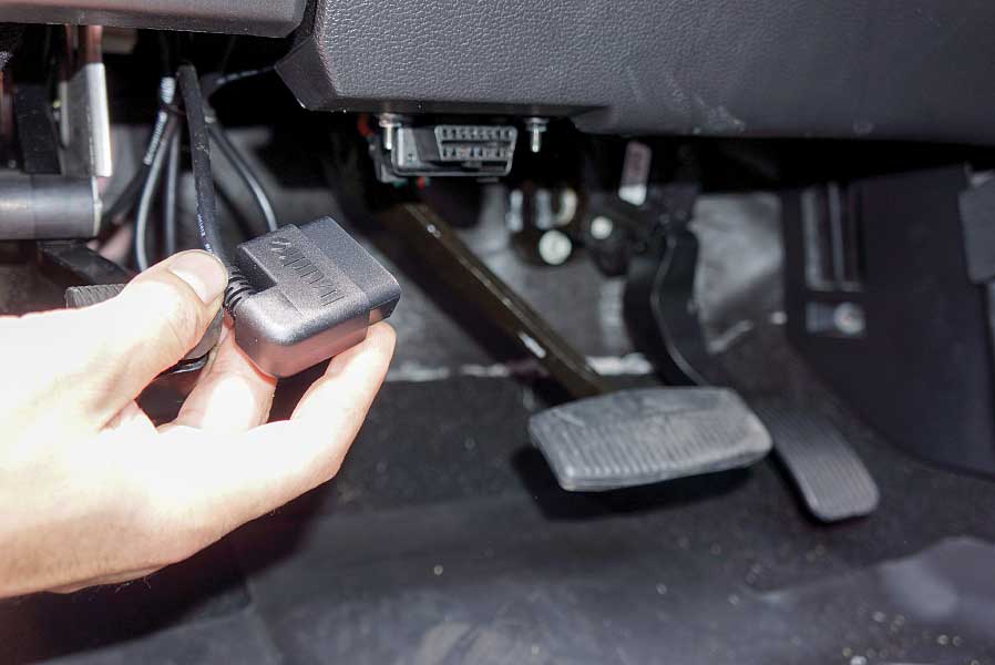 A technician connects the kit’s OBDII plug to the factory port.