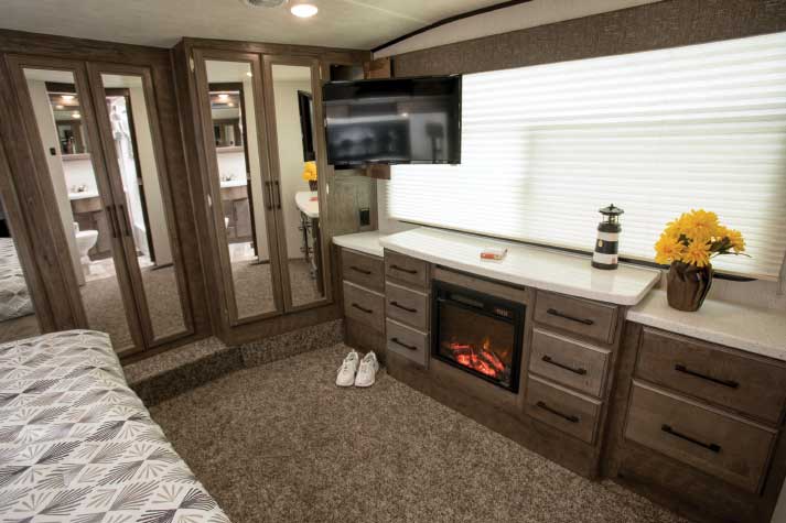 Photo of Heartland Cyclone toy hauler master bedroom with fireplace, spacious cabinets and huge picture window