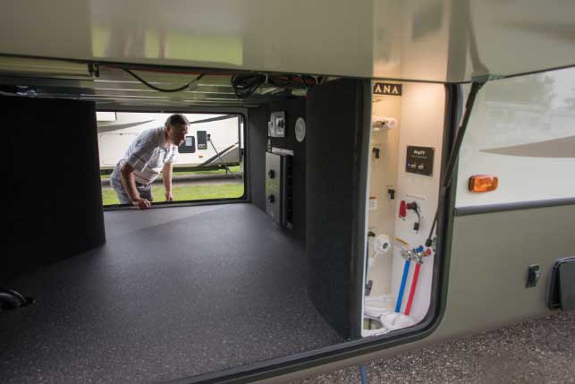 A camper peers into the Keystone Montana 3931FB fifth-wheel travel trailer heated pass-through compartment