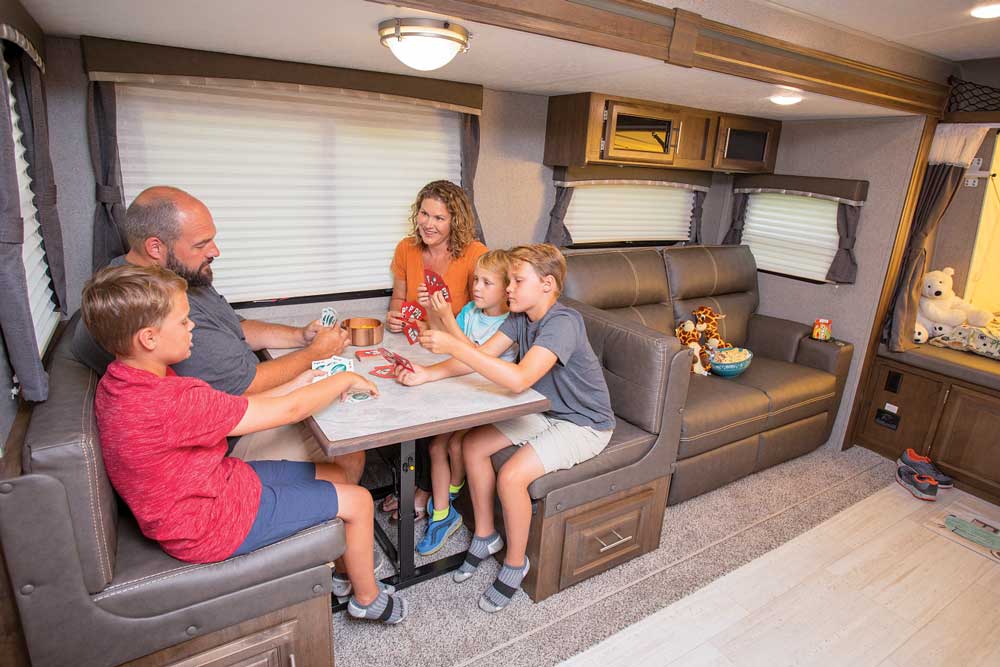 A family plays cards in the dinette of the 2020 ROCKWOOD ROO 235S hybrid travel trailer