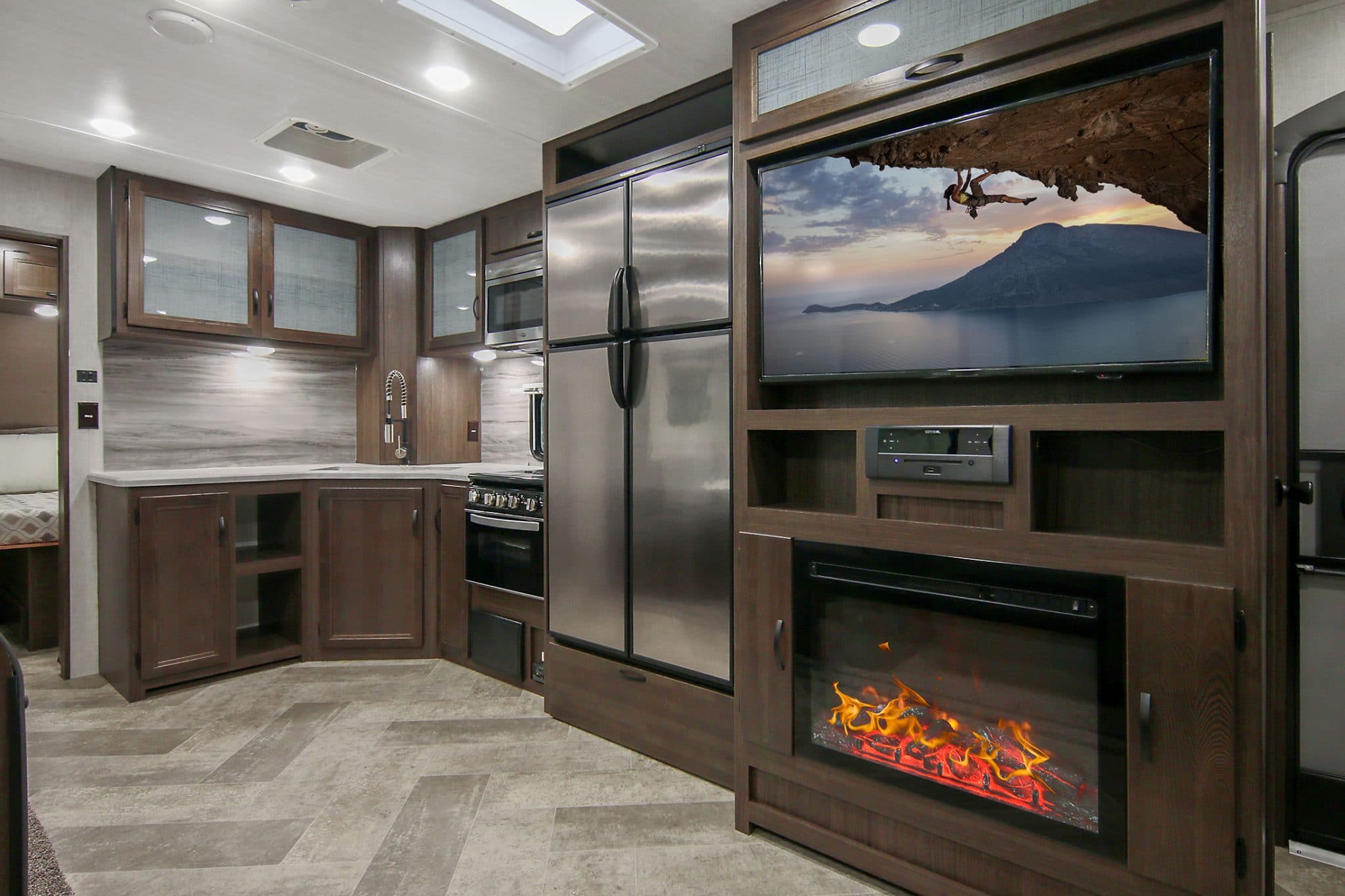 Interior of Voyage trailer showing electric fireplace and stainless refrigerator.