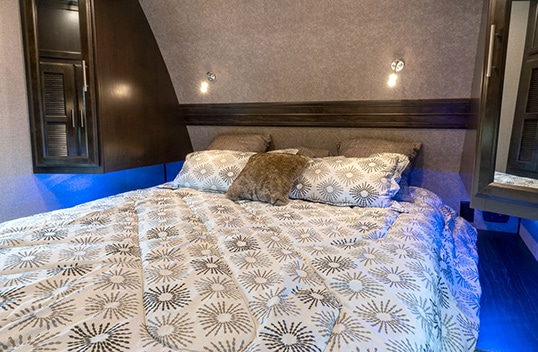 Queen bed in master bedroom with a patterned bedspread and three pillows.