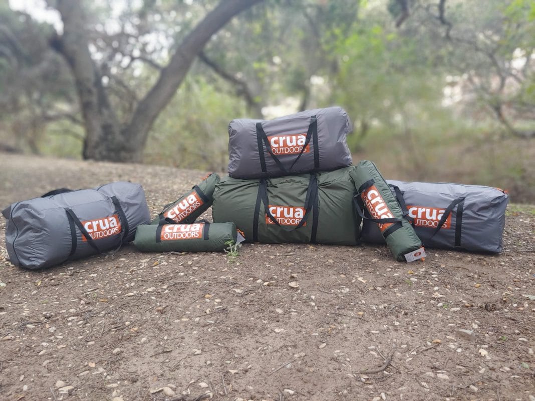 Stack of Crua tents in their bags on the floor in the woods