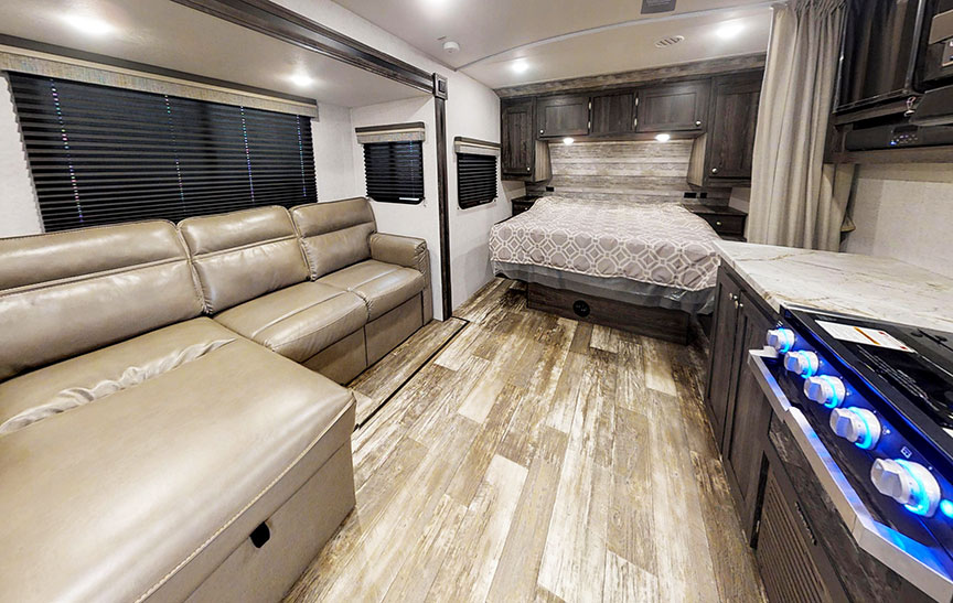 Interior of Super Lite 212FB showing queen bed and gray vinyl plank floor