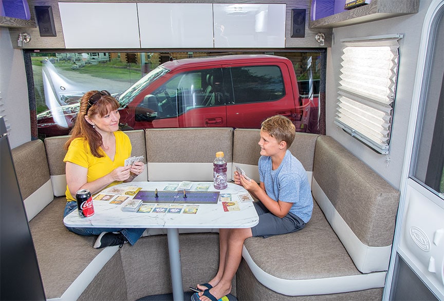 Woman and boy playing cards at dinette in Sol Horizon trailer.