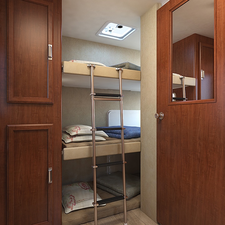 Closeup of three rear bunks with ladder and cupboards.