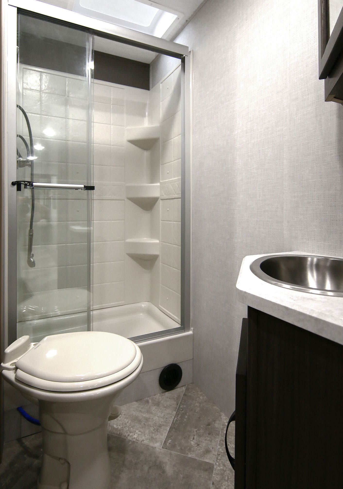 White toilet and glass-enclosed shower in trailer bathroom.