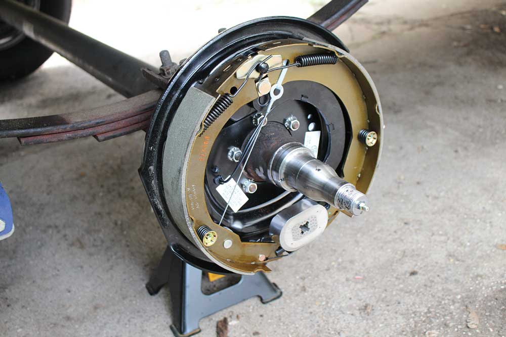 Five backing-plate nuts and washers attach the brake assembly to the axle housing.