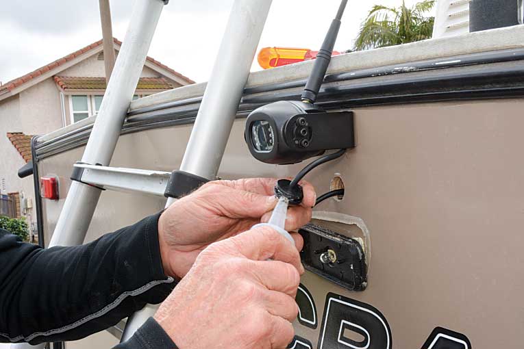 Author applies sealant to grommet during rear view camera installation.