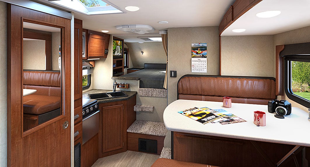 Lance 855s camper's living area, kitchen, door into bathroom and queen bed.