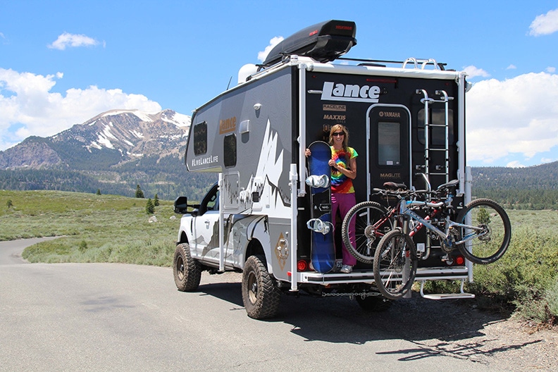 Author Donya Carlson holding snowboard on back of Lance Altimeter with bikes on rack.