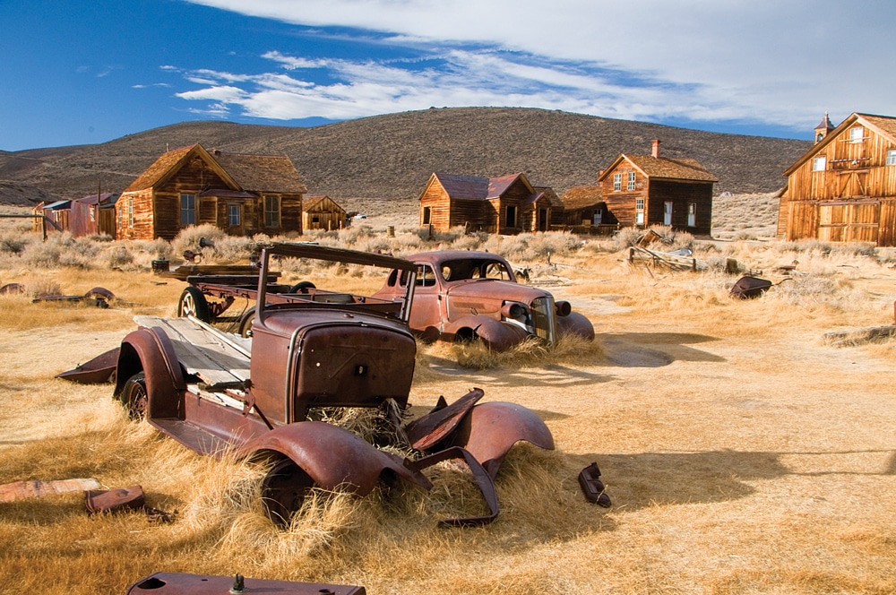 The remaining buildings at Bodie State Historic Park provide the backdrop for these abandoned autos.