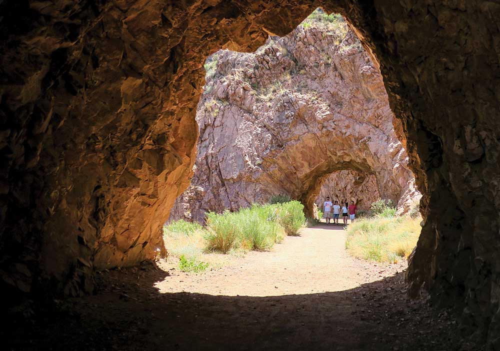 Hikers framed by cave on Tunnel Drive near Canon City, Colorado