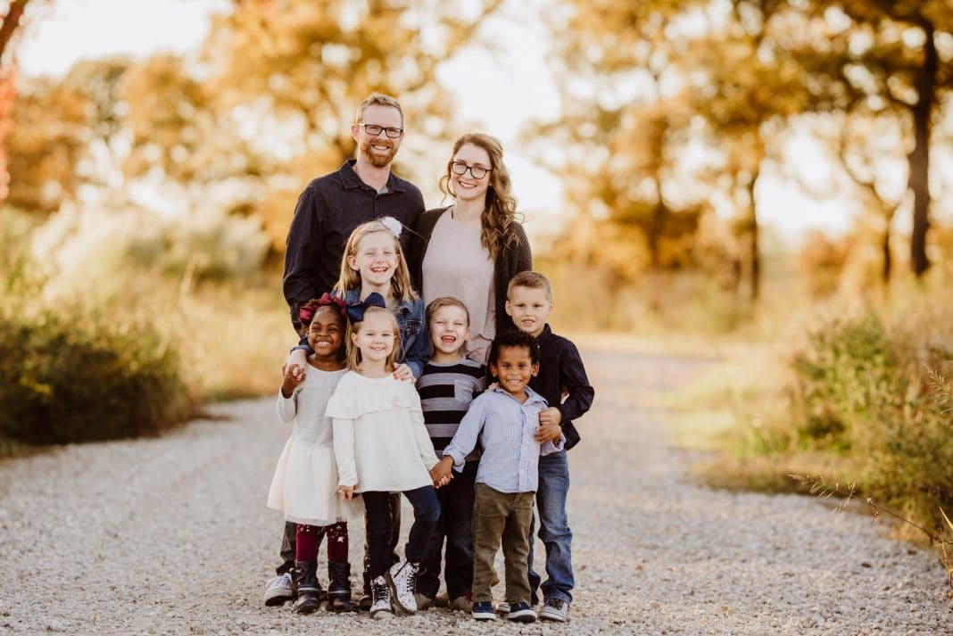 Professional family photo with mother, father and six kids standing outside