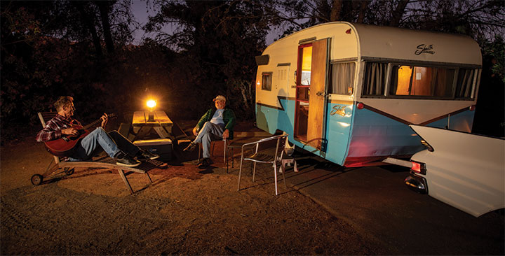 Nighttime photo with lantern on picnic table with 1959 Shasta Airflyte