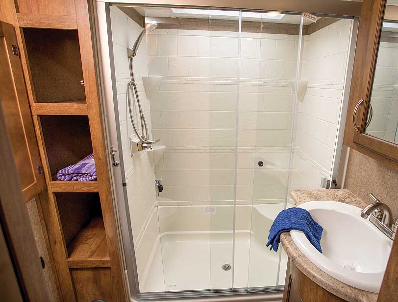 A skylight and a white molded shower liner with a corner seat give the bathroom a spa-like feel. It has deep cabinets and under-sink storage, and is accessible even with all slides retracted.