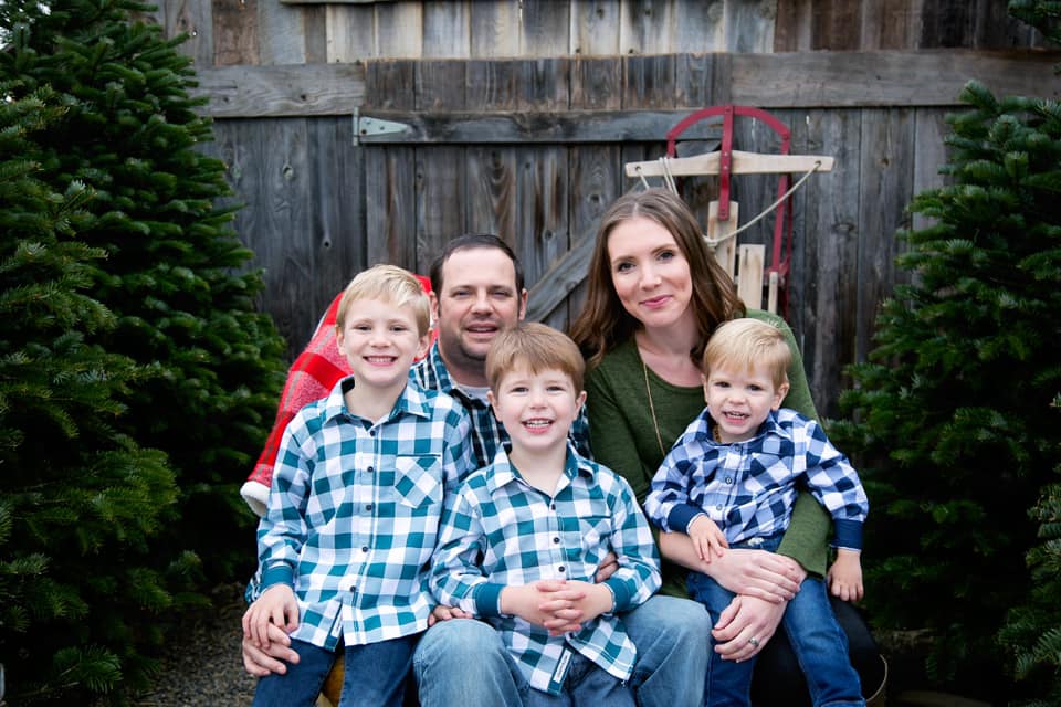 Family of five smiling at camera, kids wearing matching blue checkered shirts