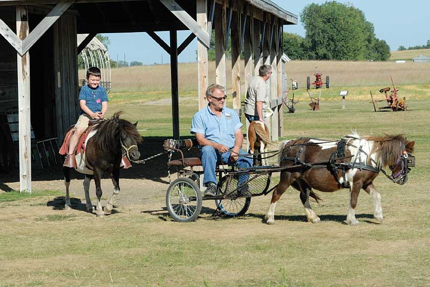 A guide at Ingalls Homestead just outside of De Smet, South Dakota, uses a pony-driven cart to take a young tourist for a pony ride.