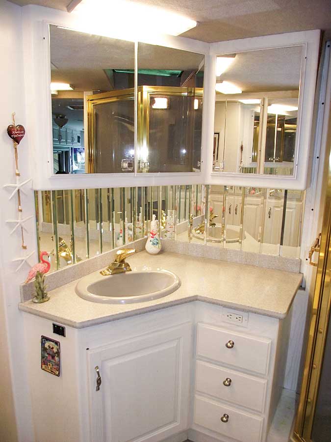 The mirrored backsplash and an emphasis on white gives a sense of space in the bathroom.