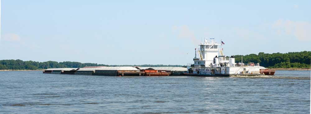 A massive “tow” of 25 barges (more than 22,000 truckloads) makes its way up the Mississippi River at historic Sainte Genevieve.
