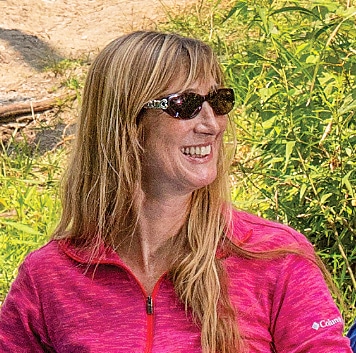 Donya Carslon in a hot-pink shirt with sunglasses and long dark blonde hair