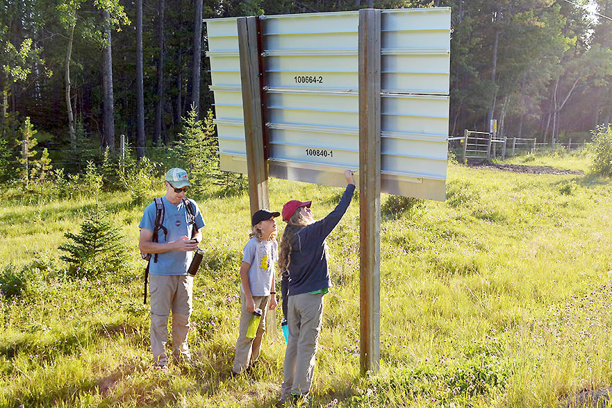 Father and two children next to highway sign