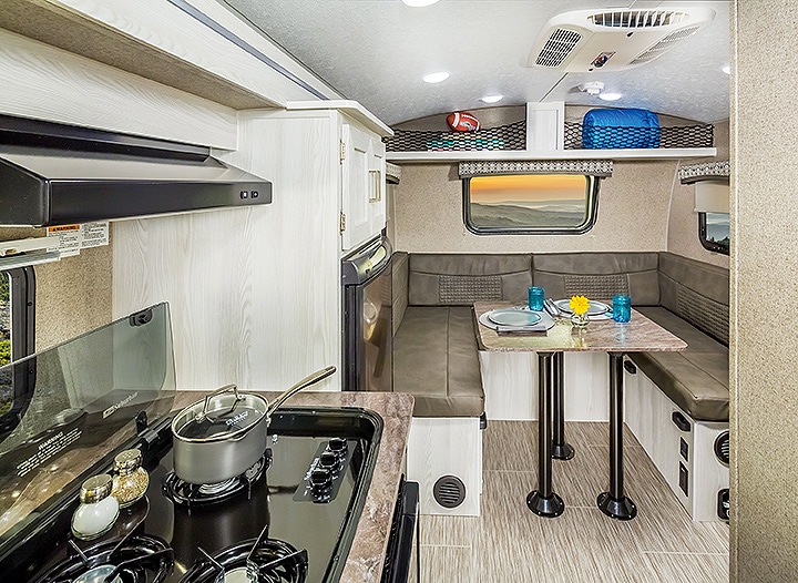 Interior of 2019 Flagstaff E-Pro E16BH showing the three-burner cooktop and U-shaped dinette.