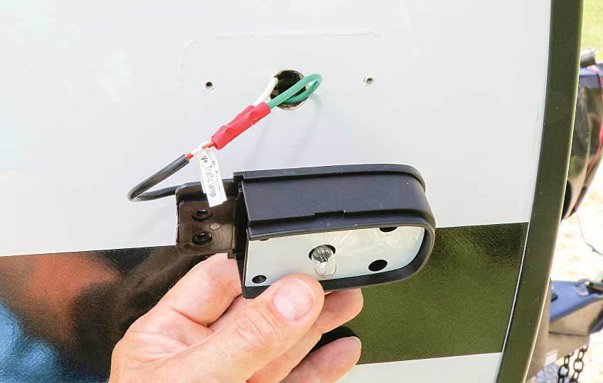 Technician attaches the Vision S system marker light to the trailer using the provided gasket and the self-tapping screws from the original light.