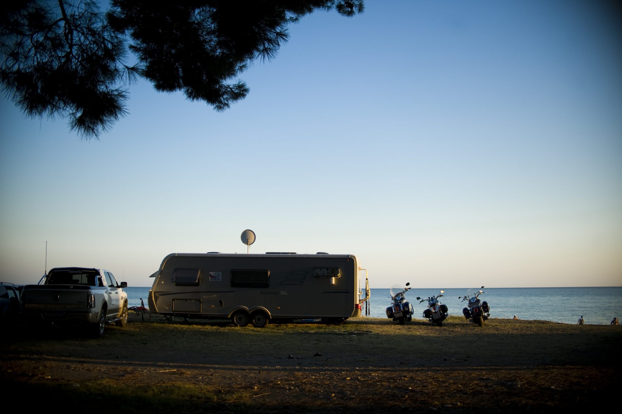 Three motorcycles parked next to motorhome along beach