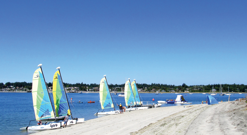 At the regional park near the tip of Goose Spit, sails punctuate the sky along the popular beach.
