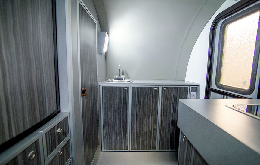 Sink and counter area of trailer with enclosed shower door closed.