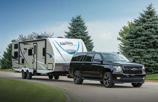 a travel trailer hitched up to a Chevy SUV